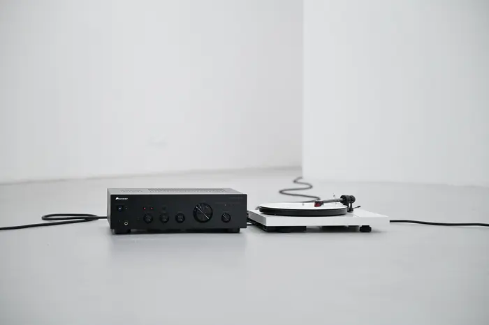 Eine Installation aus einem Plattenspieler mit weißer Schallplatte liegt ausgestreckt auf dem Boden, es läuft eine Klanginstallation zweier Personen, die das Wort JA auf Norwegisch wiederholen.