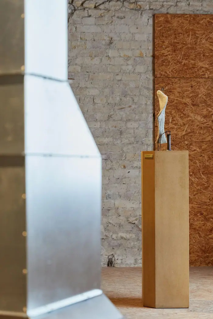 Zu sehen ist eine graue Wollsocke drapiert auf einem Podest