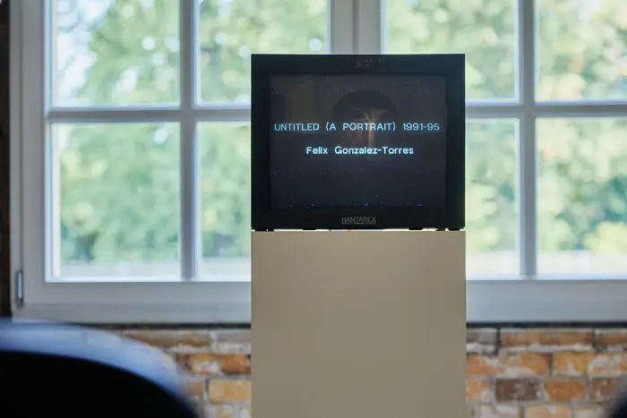 Zu sehen ist ein Bildschirm vor einem Doppelfenster, im Bildschirm ist der Titel des Werks zu lesen.