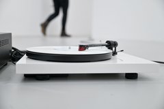 Eine Installation aus einem Plattenspieler mit weißer Schallplatte liegt ausgestreckt auf dem Boden, es läuft eine Klanginstallation zweier Personen, die das Wort JA auf Norwegisch wiederholen.