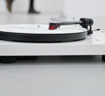 Eine Installation aus einem Plattenspieler mit weißer Schallplatte liegt ausgestreckt auf dem Boden, es läuft eine Klanginstallation zweier Personen, die das Wort JA auf Norwegisch wiederholen.