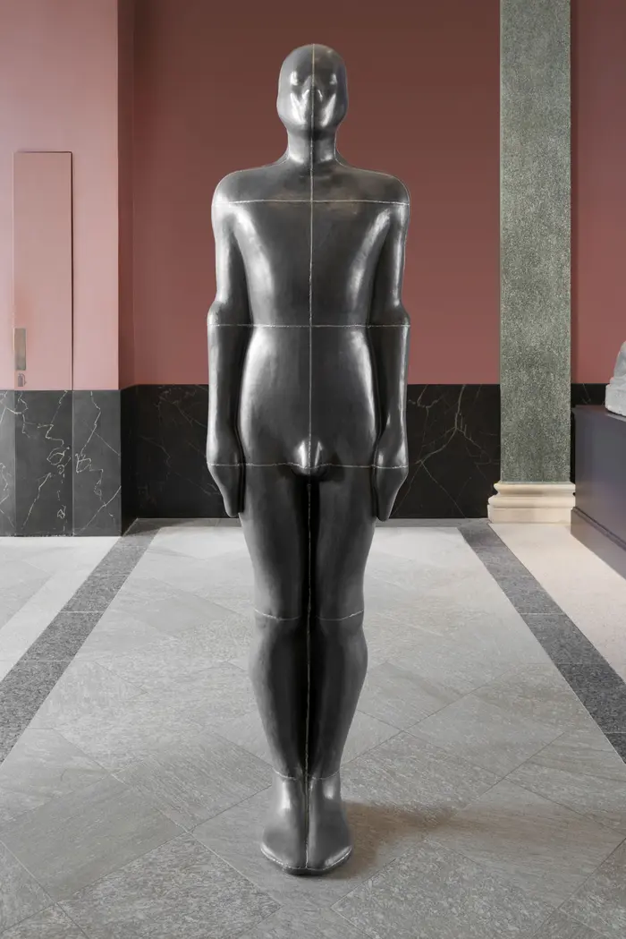 Zu sehen ist das Werk "Learning to see III" von Antony Gormley aus dem Jahr 1993, einem in Metallplatten zusammen geschweißten einstigen Abgusses des Künstlers. Das Werk ist in der Antikenhalle des Semperbaus gegenüber einer weiteren Arbeit Gormleys  installiert.