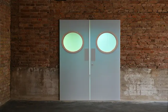 A K Dolven, "The doors", 2006 Die Videoprojektion der Künstlerin A K Dolven wirft das Bild zweier realgroßer Türen auf eine Ziegelwand. Die Türen schwingen leicht auf und wieder zu.