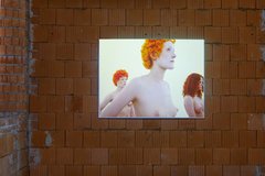 Zu sehen ist eine Videoprojektion vor einer unverputzten Wand mit drei oberkörperfreien Frauen
