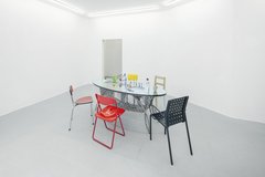 Raum mit einem gedeckten Tisch in der Mitte, ringsherum verschiedene Stühle
