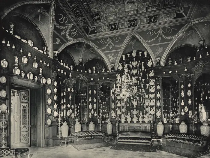 Zu sehen ist eine historische Aufnahme des Porzellankabinetts im Turmzimmer des Dresdner Residenzschlosses. Die Konsolen sind gefüllt mit Prozellanobjekten.