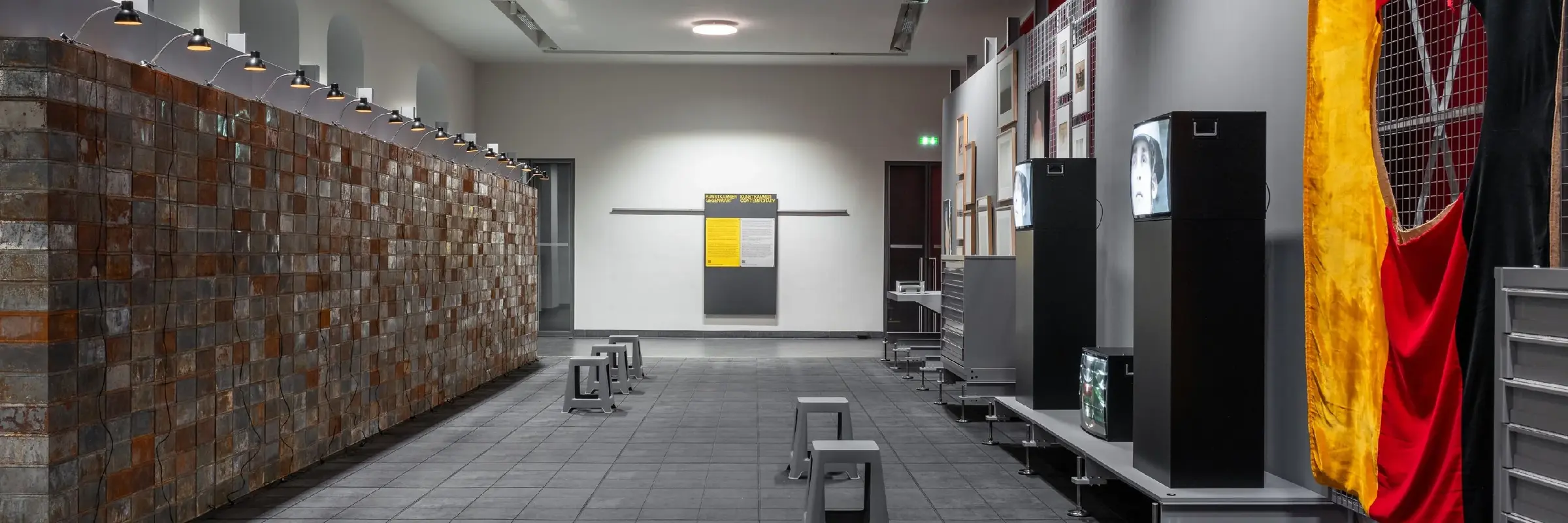 Das Bild zeigt eine an ein Depot angelehnte Ausstellungsarchitektur mit Werken der Schenkung Sammlung Hoffmann, des Kunstfonds, des Kupferstich-Kabinetts und des Albertinums. Das Bild zeigt einen Blick in den Ausstellungsraum, unter anderem sind Werke von Christian Boltanski, Georg Herold oder Marcel Odenbach zu sehen. 