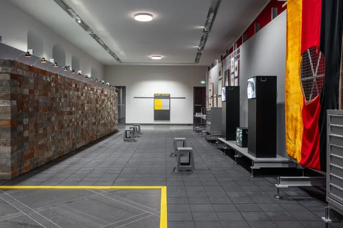 Das Bild zeigt eine an ein Depot angelehnte Ausstellungsarchitektur mit Werken der Schenkung Sammlung Hoffmann, des Kunstfonds, des Kupferstich-Kabinetts und des Albertinums. Das Bild zeigt einen Blick in den Ausstellungsraum, unter anderem sind Werke von Christian Boltanski, Georg Herold oder Marcel Odenbach zu sehen. 