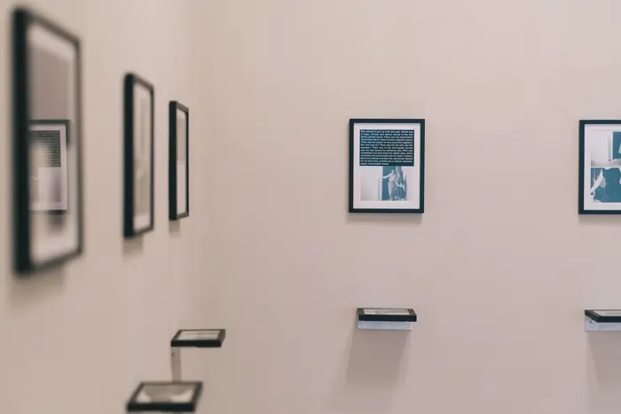 Zu sehen sind kleine Bilder an der Wand, unter jedem Bild hängt ein horizontal angebrachtes Bild in der Wand